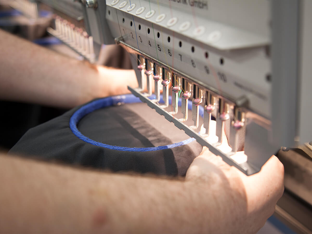 Produktionsmitarbeiter arbeitet an computergesteuerter Stickmaschine – KinzigStick